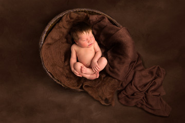 Baby sleeping in old wooden  bowl