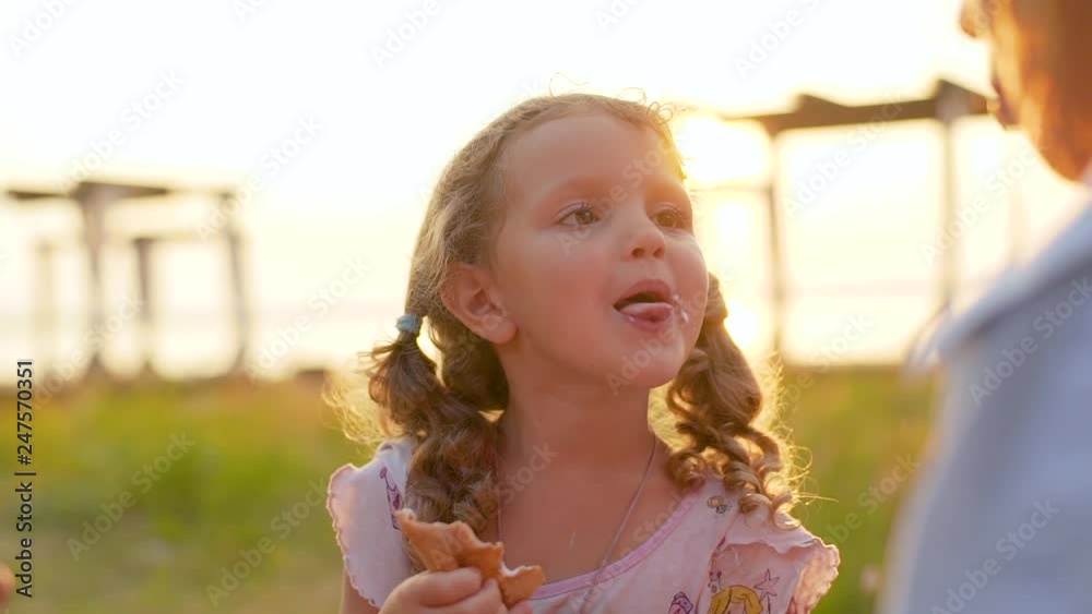 Close-up slow motion. Cute curly little girl shows the language and kissing mom. A girl without a tooth with a wide smile. Sunset light background. Real emotions Close-up slow motion. Cute curly little girl shows the language and kissing mom. A girl without a tooth with a wide smile. Sunset light background. Real emotions