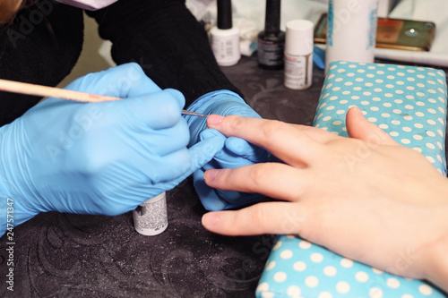 beautician applying nail polish to female nail in a nail salon  close up