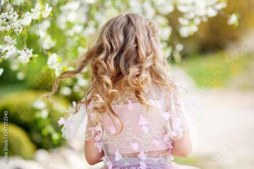 Beautiful young girl in pink dress in the garden with blosoming  cherry trees. Cute girl  having fun and enjoying photo