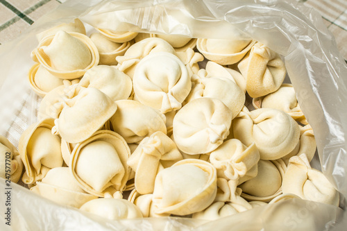 Handmade siberian dumplings are in plastic bag on table.