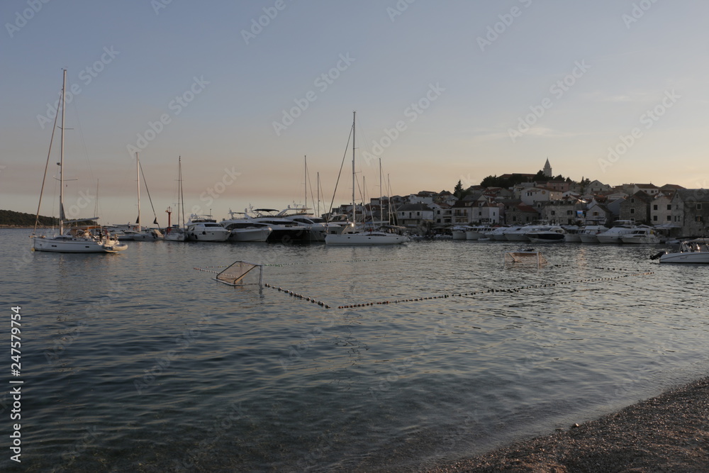 View of the marina and the old town in Primosten. Sailboats, yachts on the Adriatic Sea. Warm, summer, evening on the Croatian coast. Mediterranean vegetation, riviera, sunset, Croatia