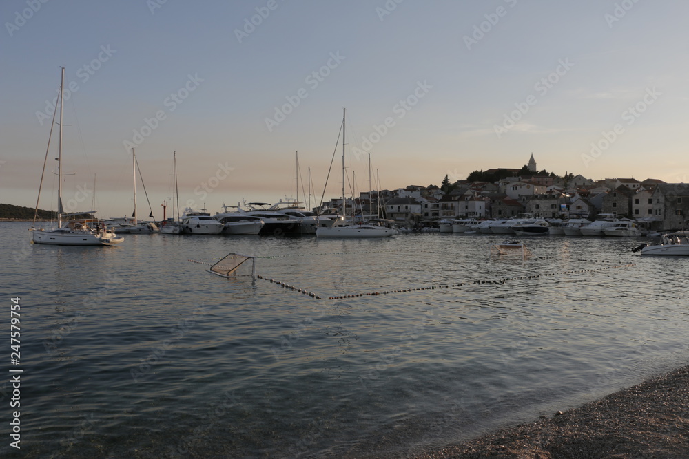 Fototapeta premium View of the marina and the old town in Primosten. Sailboats, yachts on the Adriatic Sea. Warm, summer, evening on the Croatian coast. Mediterranean vegetation, riviera, sunset, Croatia