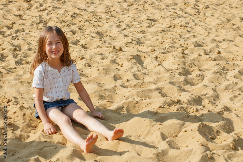 The girl sits on the golden sand near the sea The girl sits on the golden sand near the sea