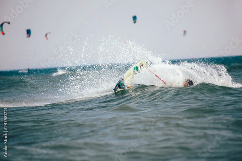 Professional kiter makes the difficult trick on a beautiful background. Kitesurfing Kiteboarding action photos man among waves quickly goes