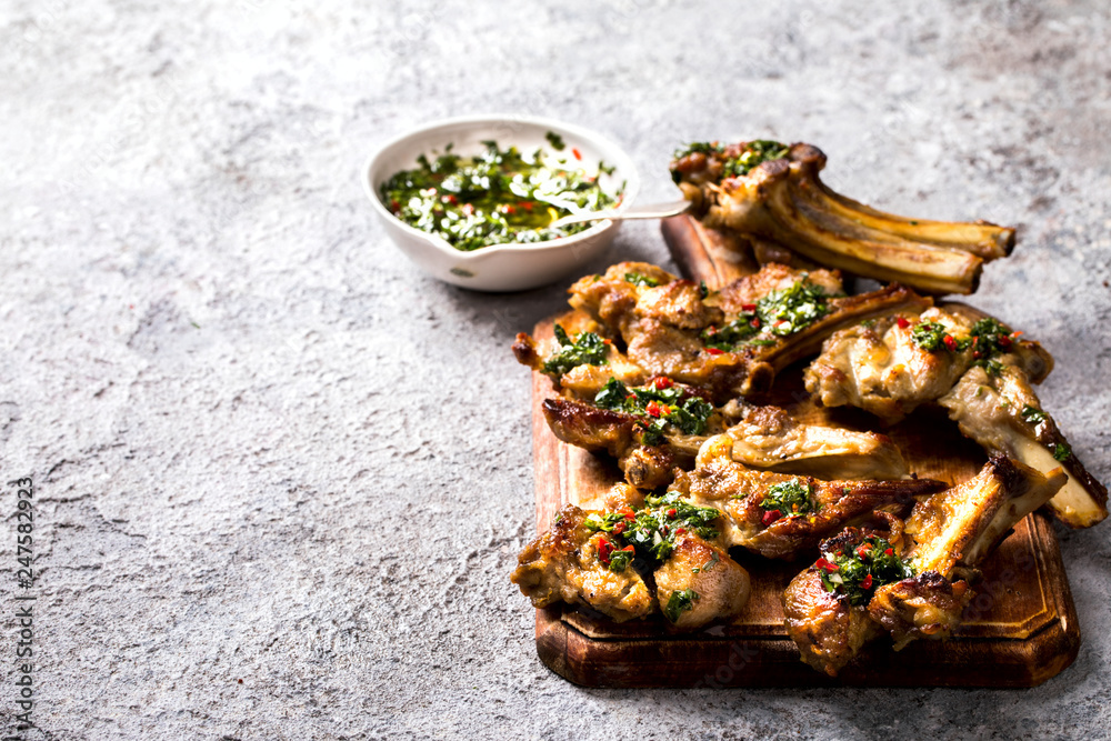 Argentinian green Chimichurri.Raw homemade sauce.Beef steak on the bone on gray stone slate background.Traditional snack. Copy space for Text. Argentinian green Chimichurri.Raw homemade sauce.Beef steak on the bone on gray stone slate background.Traditional snack. Copy space for Text.