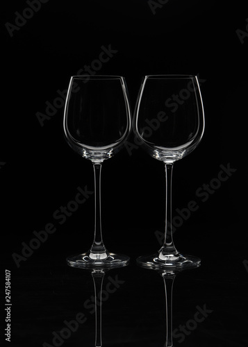 Two wine glasses stand side by side on a black background without glare close-up