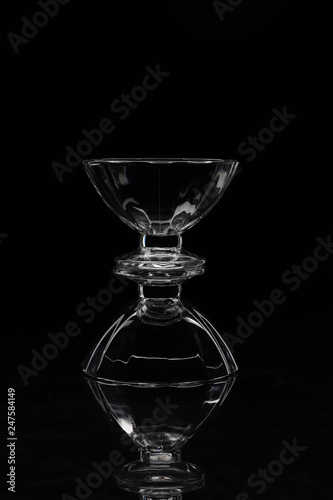 two transparent glass vases on top of each other on a backlit black background