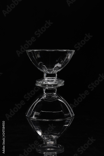 two transparent glass vases on top of each other on a black background and their reflection