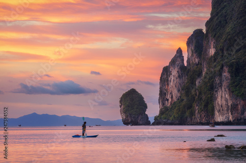 Sunset Phi Phi island Loh Dalum beach with man on SUP board and limestone rocks on background photo