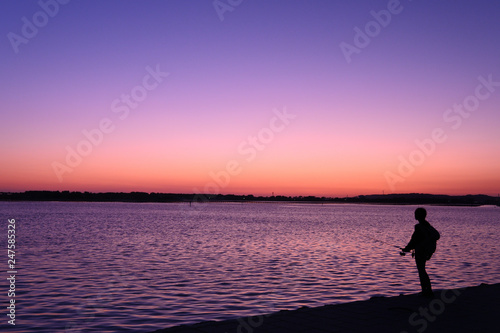 夕焼けの弁天島で釣りをする人