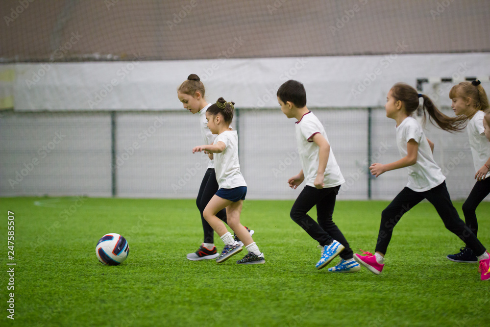Children playing football indoors. Kids running before the ball