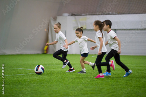 Children playing football indoors. Kids running on the field after the ball © KONSTANTIN SHISHKIN