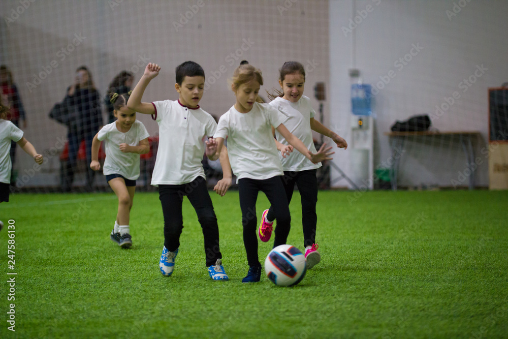 Children playing football indoors. Children lead the ball