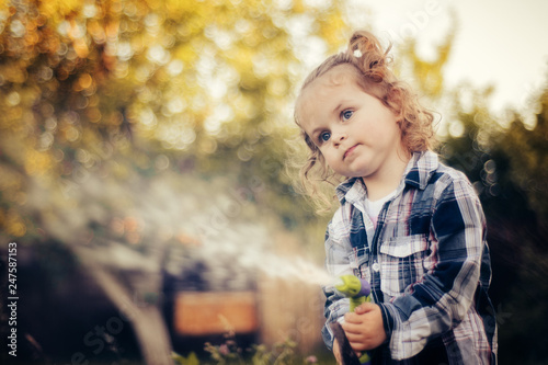 Young pretty girl spraying water with a hose