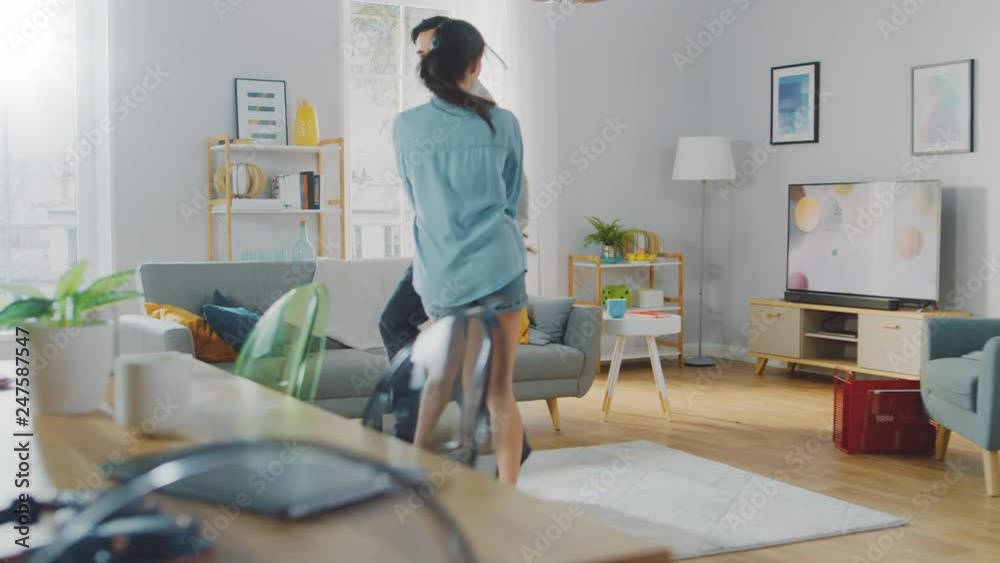 Happy Beautiful Couple is Having Fun and Actively Dancing in their Cozy Living Room at Home. They Smile and Laugh. Slow Motion Shot. Happy Beautiful Couple is Having Fun and Actively Dancing in their Cozy Living Room at Home. They Smile and Laugh. Slow Motion Shot.