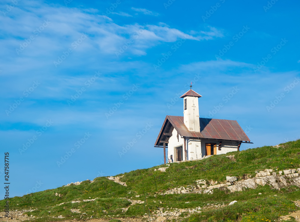 Mountain chapel against blue sky. Dolomites, Italy