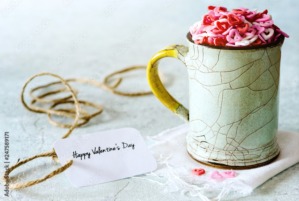 Valentine's day: sugar candies of hearts in a cup on delicate background Valentine's day: sugar candies of hearts in a cup on delicate background