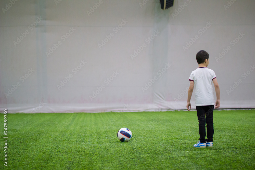 A little boy standing on a football field