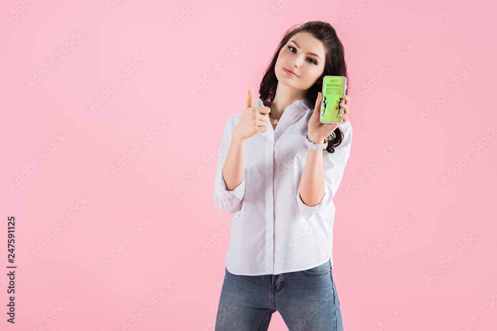 beautiful girl showing thumb up and smartphone with shopping app on screen, isolated on pink beautiful girl showing thumb up and smartphone with shopping app on screen, isolated on pink