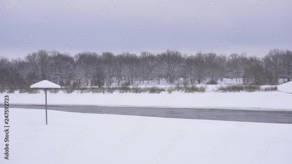 Winter empty beach in the snow, in the background of the forest, copy space, water
