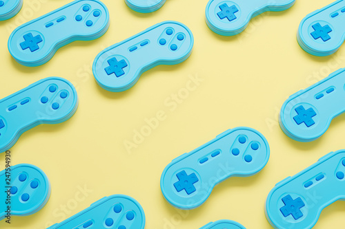 Background made of blue retro gamepad on the yellow table. Top view. 3d render