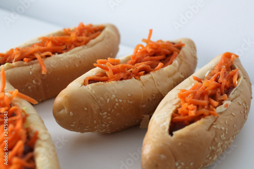 Incredibly delicious and juicy hotdogs with carrots on the white table. 