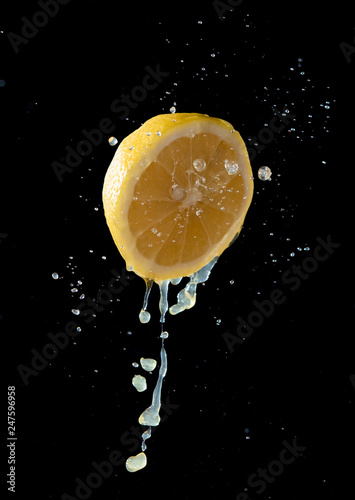 Lemom slice with juice splash isolated on black background photo