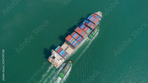 Aerial view container ship and tug boat going to sea port for logistic, import export, shipping or transportation.