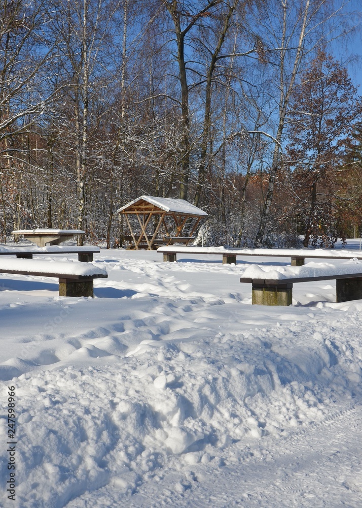 Rastplatz mit Sitzgruppe am Waldrand schneebedeckt winterlich sonnig