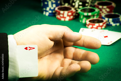 Gambling fraud concept. Card hidden in the sleeve on the background of chips