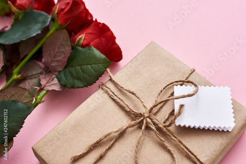 Fototapeta Naklejka Na Ścianę i Meble -  What is inside? A special gift for her with fresh red roses and white piece of paper for love words