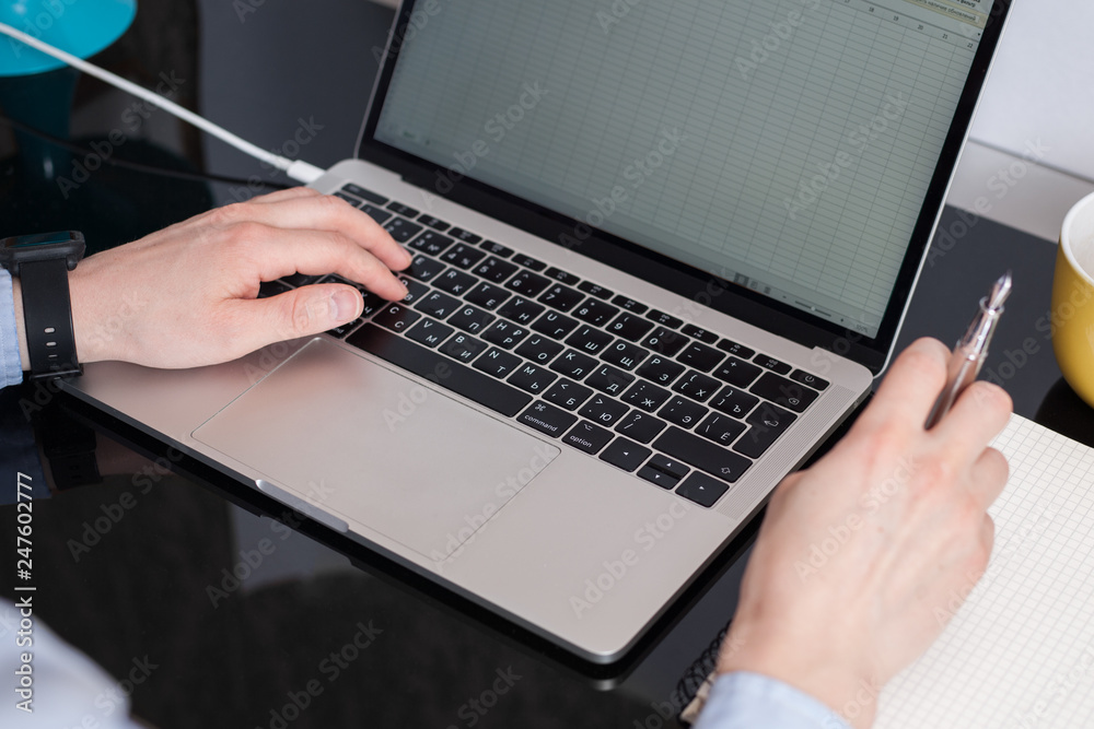 Close-up of businessman hands typing and making notes Close-up of businessman hands typing and making notes