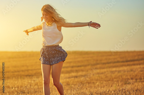 Cute young woman jumping in a wheat field.