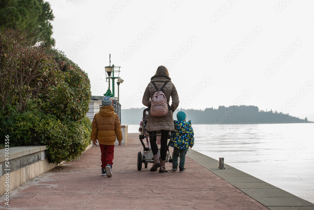 Obraz premium Young mother walking on a promenade along the sea pushing a stroller