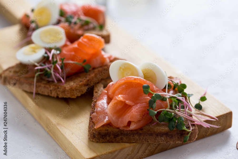 Toasts with smoked salmon garnished with quail egg and radish sprouts Toasts with smoked salmon garnished with quail egg and radish sprouts