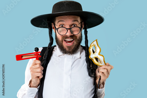 Portrait of a young orthodox Hasdim Jewish man with wooden Grager Ratchet at Jewish festival of Purim at studio. The purim, jewish, festival, holiday, celebration, judaism, pastry, tradition, cookie photo