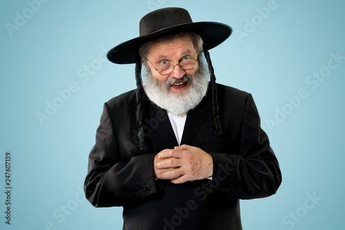 Obraz na plátně Portrait of old senior orthodox Hasdim Jewish man with wooden Grager Ratchet at Jewish festival of Purim at studio