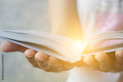 Wallpaper Mural Light coming from book in woman's hands in gesture of giving, offering. Concept of wisdom, religion, reading, imagination. Torontodigital.ca