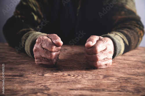 Old woman hands on wooden table.