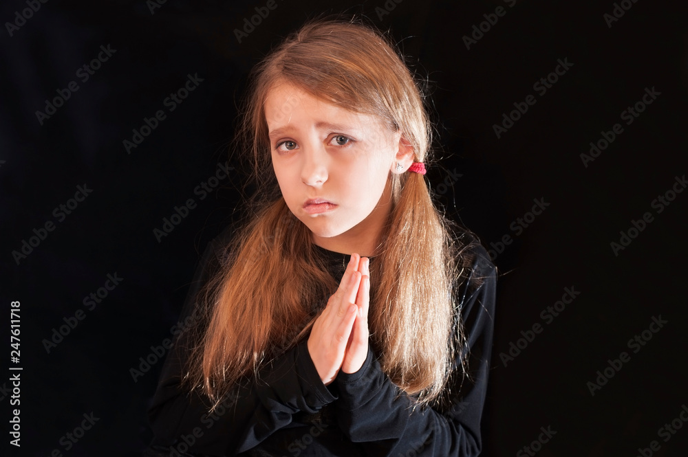 The young girl with a sad, pleading face, hands in front of her in prayer begs God to help The young girl with a sad, pleading face, hands in front of her in prayer begs God to help