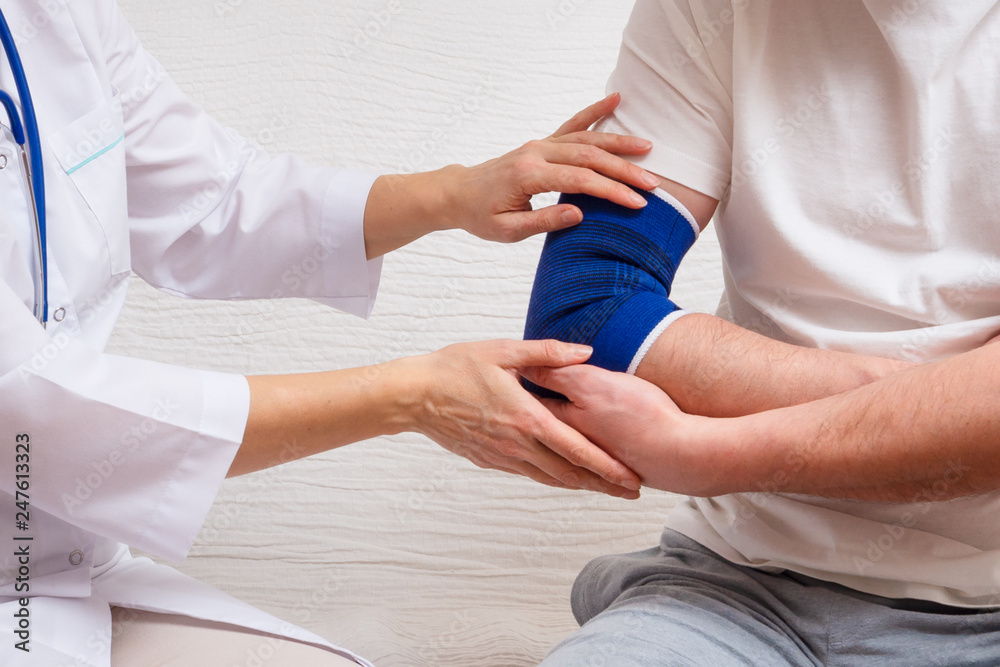 doctor helps the patient to use bandage on the elbow doctor helps the patient to use bandage on the elbow
