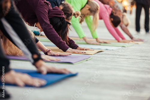 Close up hands of yoga group doing Downward facing dog pose, adho mukha svanasana exercise outdoor on fitness terrace, ?alm and relax concept, wellness and healthy lifestyle © Rithor