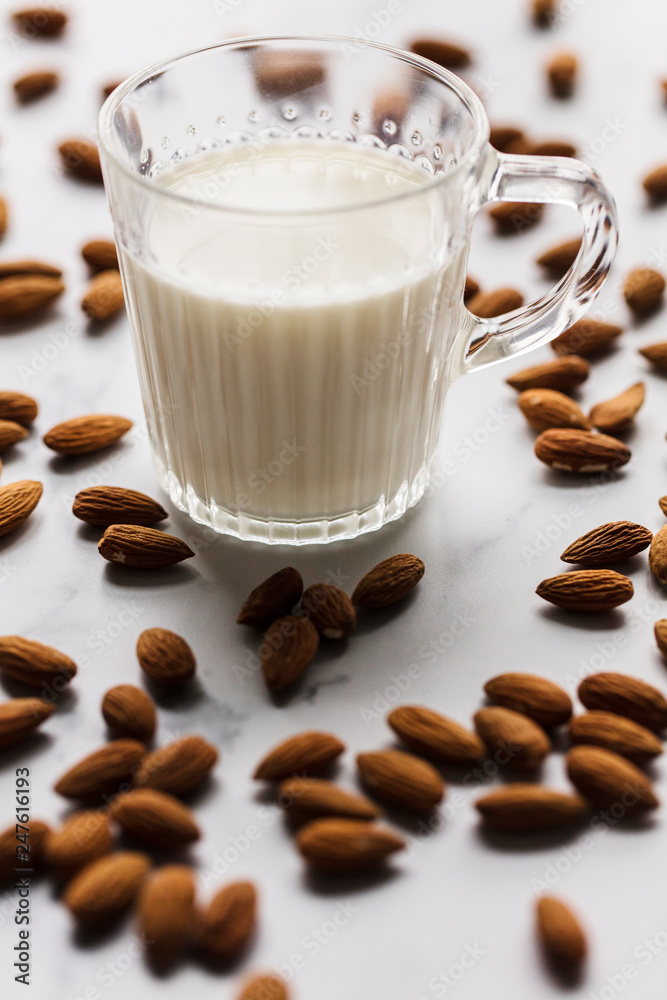 Almond milk in a glass surrounded by organic almonds Almond milk in a glass surrounded by organic almonds