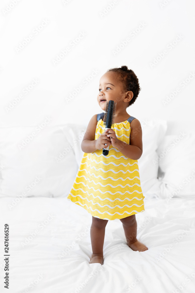 Toddler standing on bed holding hairbrush Toddler standing on bed holding hairbrush