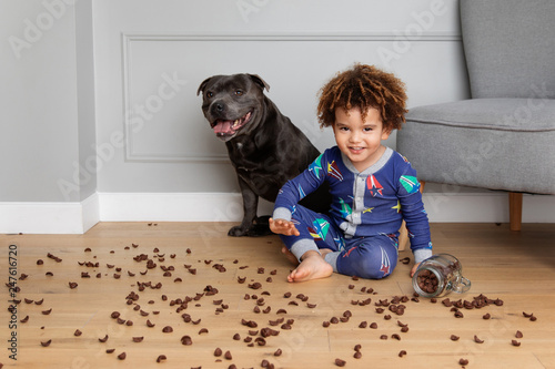 Mischievous boy and dog making mess with cereals on floor