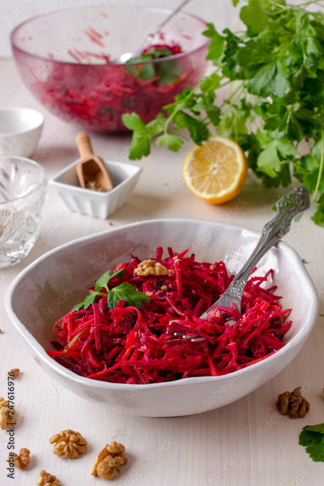 Healthy raw vegan beetroot salad with carrot and walnuts in a bowl on white wooden table. Natural organic food concept. Healthy diet Healthy raw vegan beetroot salad with carrot and walnuts in a bowl on white wooden table. Natural organic food concept. Healthy diet