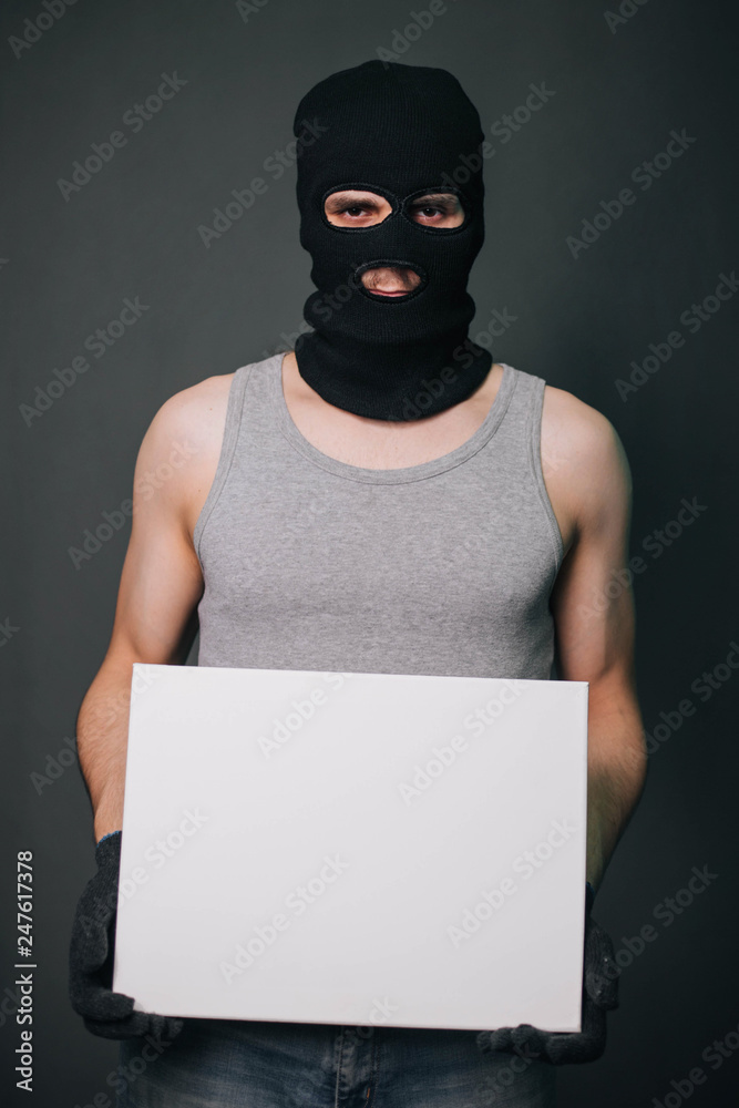 A man in a black mask holds a white sheet. A guy in a balaclava and wearing gloves holds a white empty square. A man on a gray background holds a canvas. A man in a black mask holds a white sheet. A guy in a balaclava and wearing gloves holds a white empty square. A man on a gray background holds a canvas.