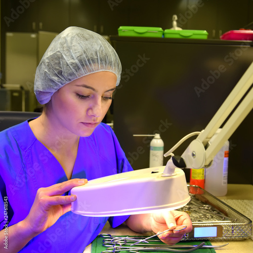 A young woman works in a hospital as a  medical hygiene technician. She is dressed  in special medical hygiene clothing and  carries out hygiene disinfecting and logistic tasks.