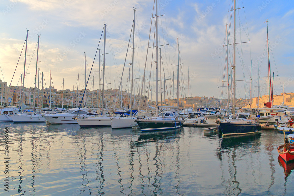 Sunset over moored yachts in a quiet bay in Malta.